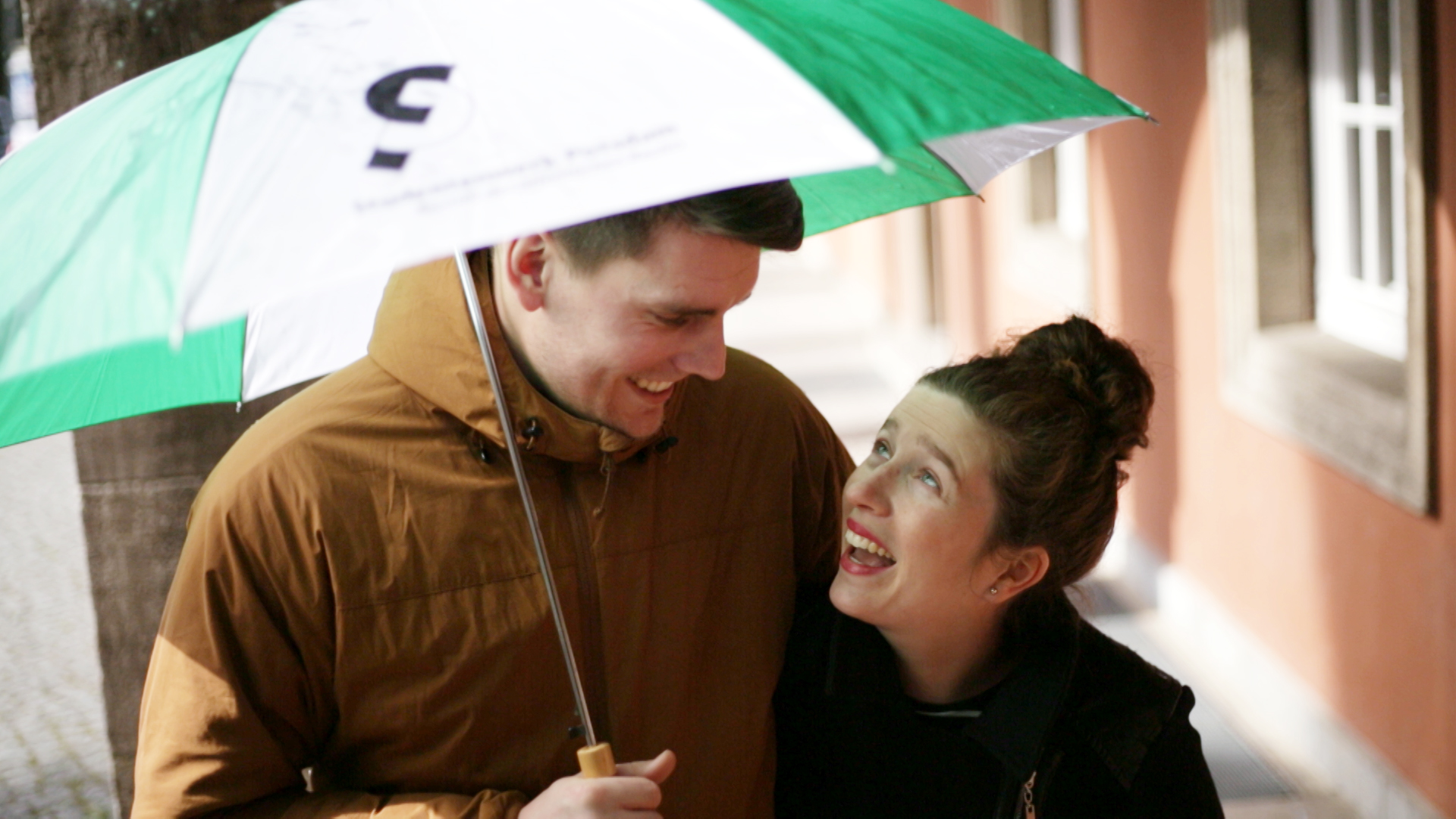 Paar läuft durch Regen mit Schirm 